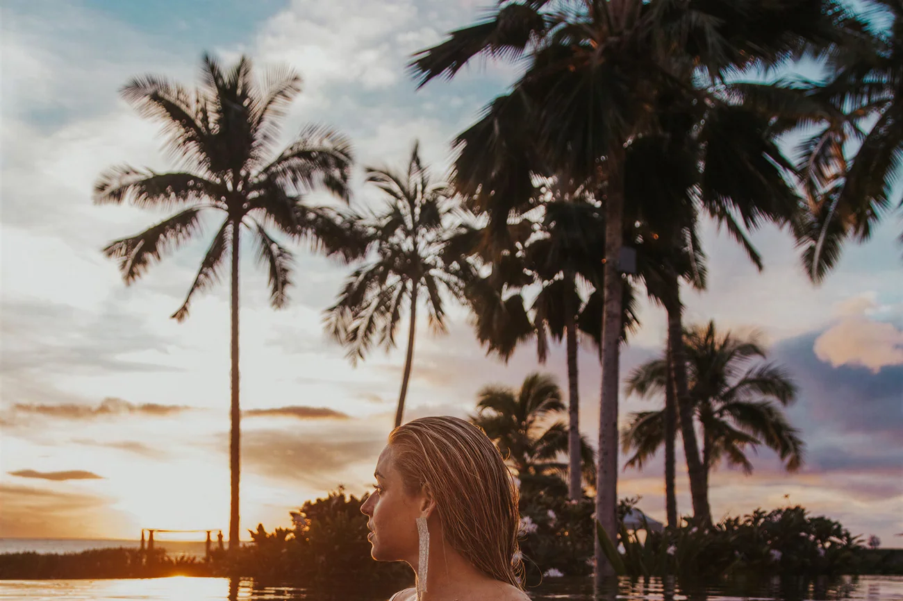 Infinity pool at sunset framed by palms over the sea